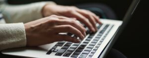 Two hands typing on a keyboard of a laptop